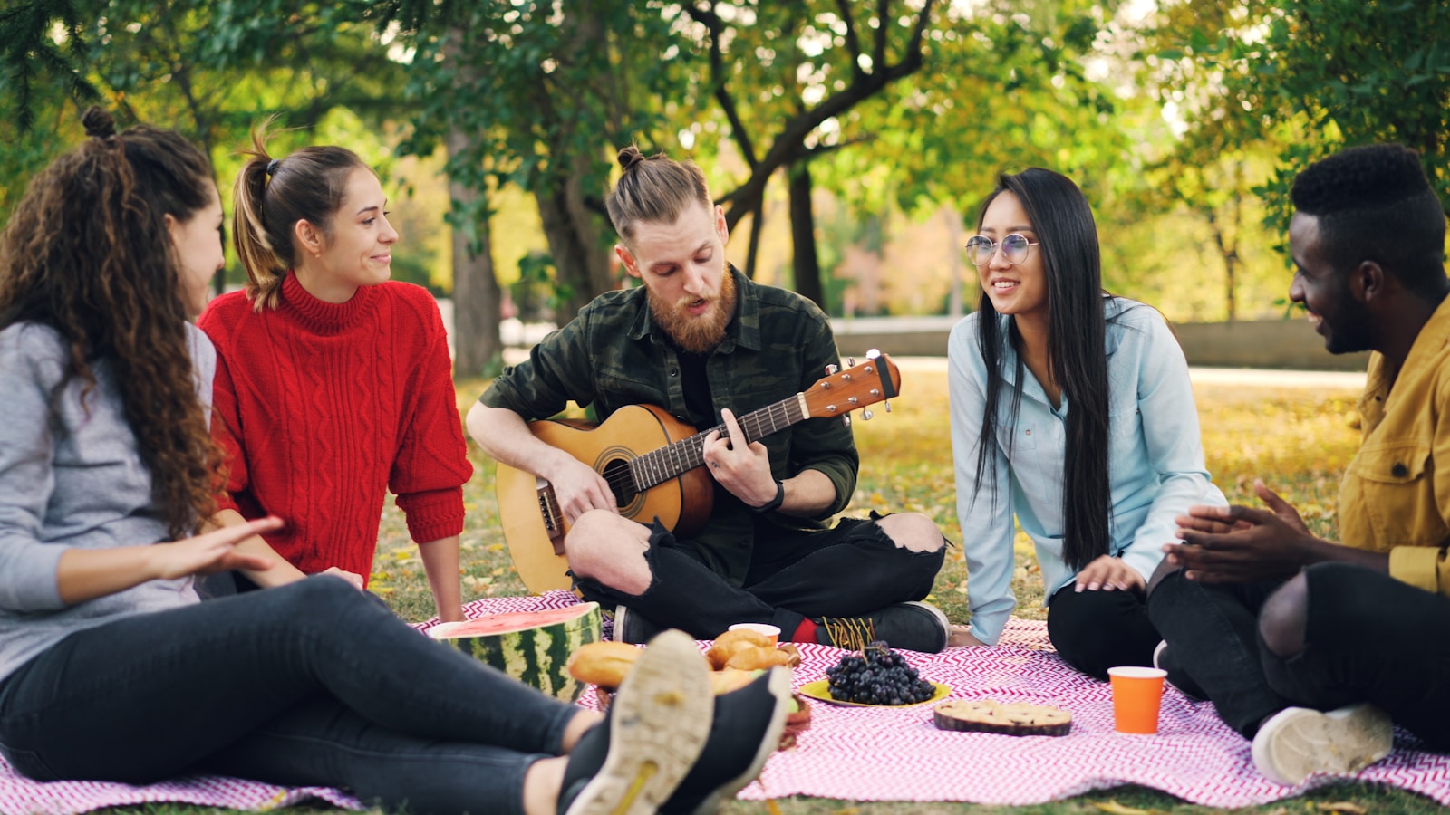 Friends enjoy a picnic with music in the park.